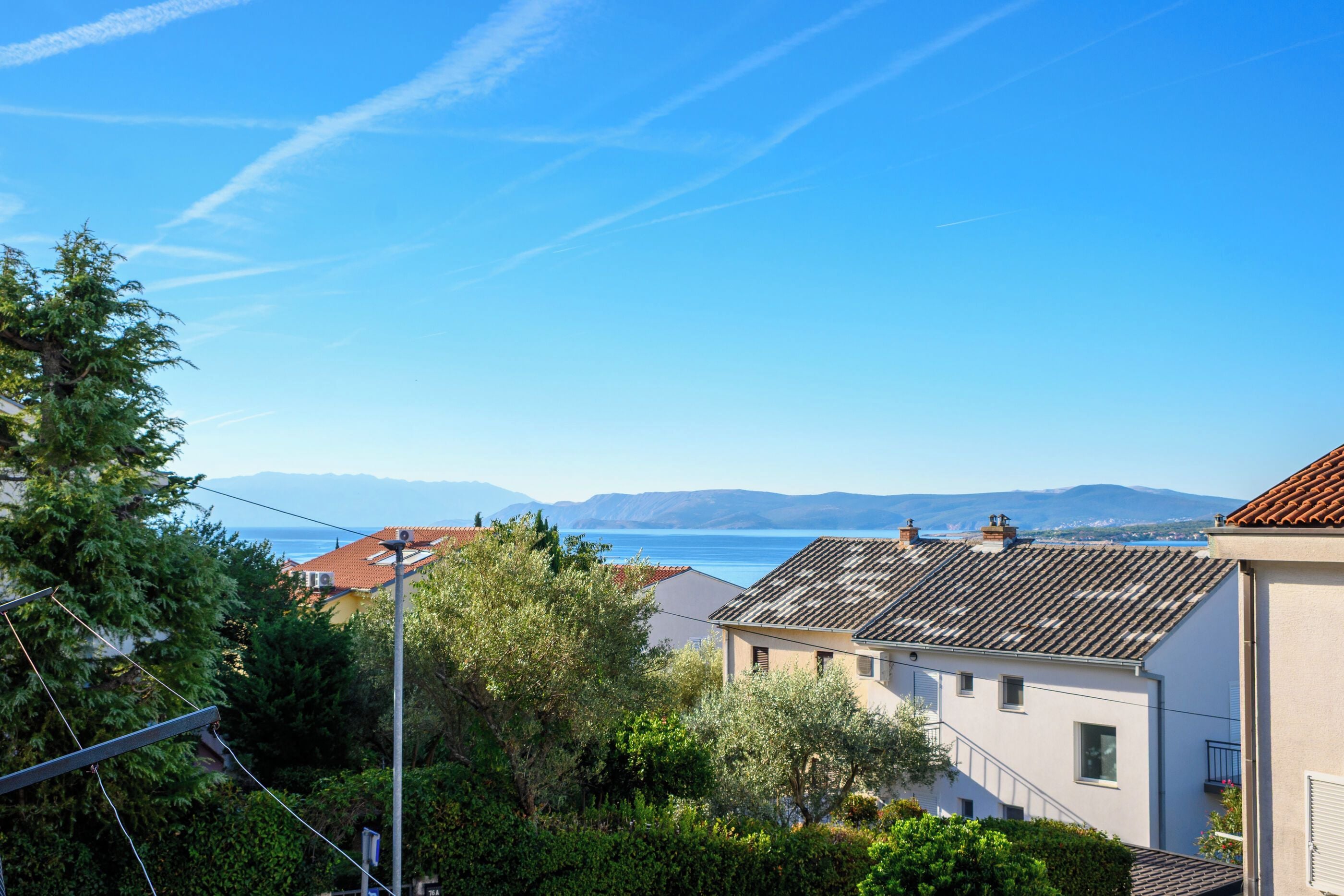 A residential area with houses, a clear sky, and a distant view of the sea.