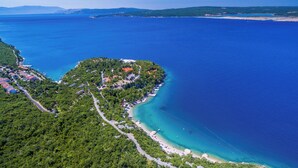 Vista aérea de uma área costeira com praia, um pequeno povoado com casas e um mar azul cristalino.
