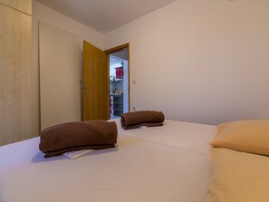 A bedroom with a bed, two towels, a wardrobe, and an open door leading to a bathroom. - Apartments Ninac (Klenovica)