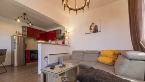 Ein modernes Wohnzimmer mit einem grauen Sofa, einem Glastisch und einer flauschigen Decke.