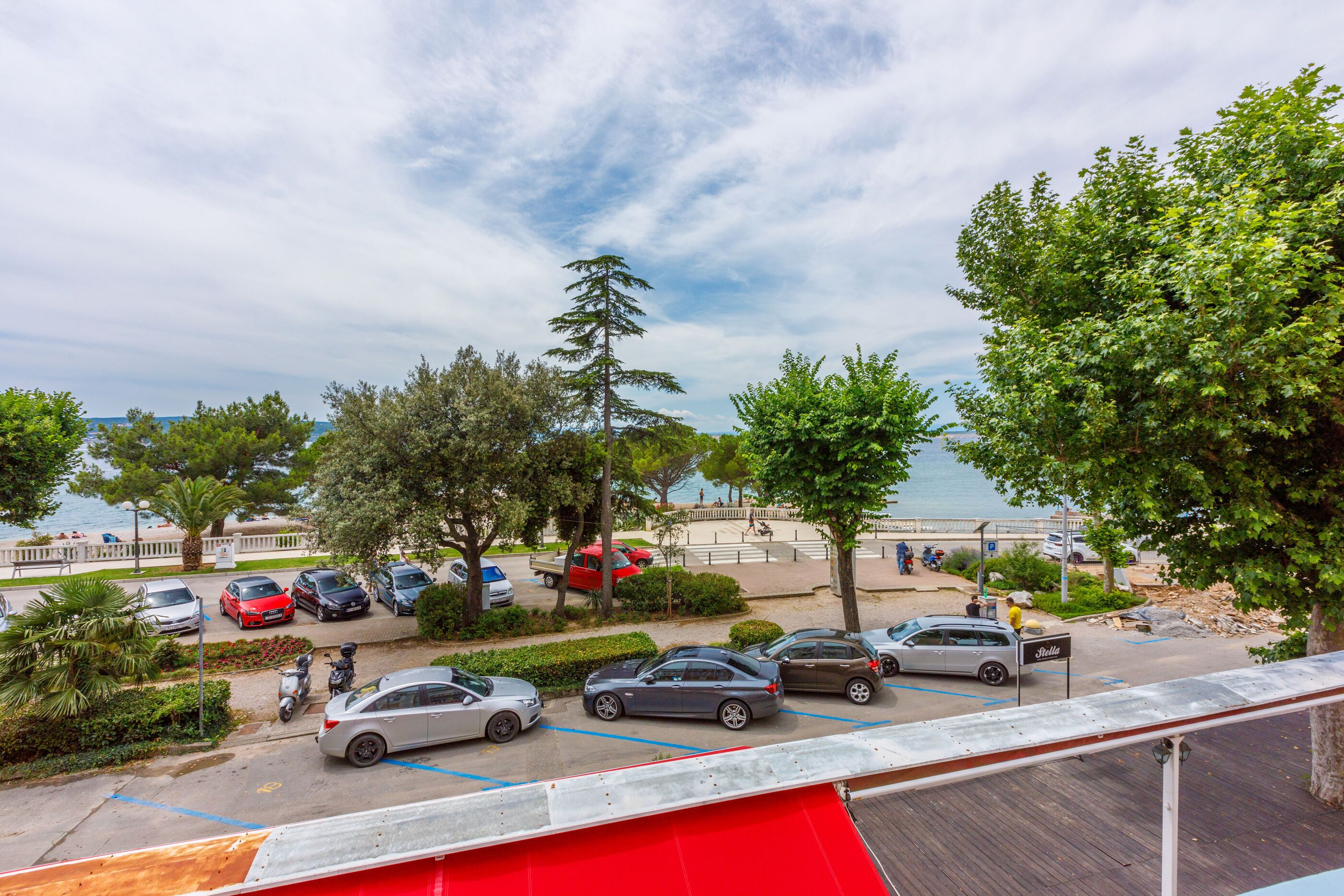 Ein Parkplatz mit Autos und einem Fußweg nahe am Strand.