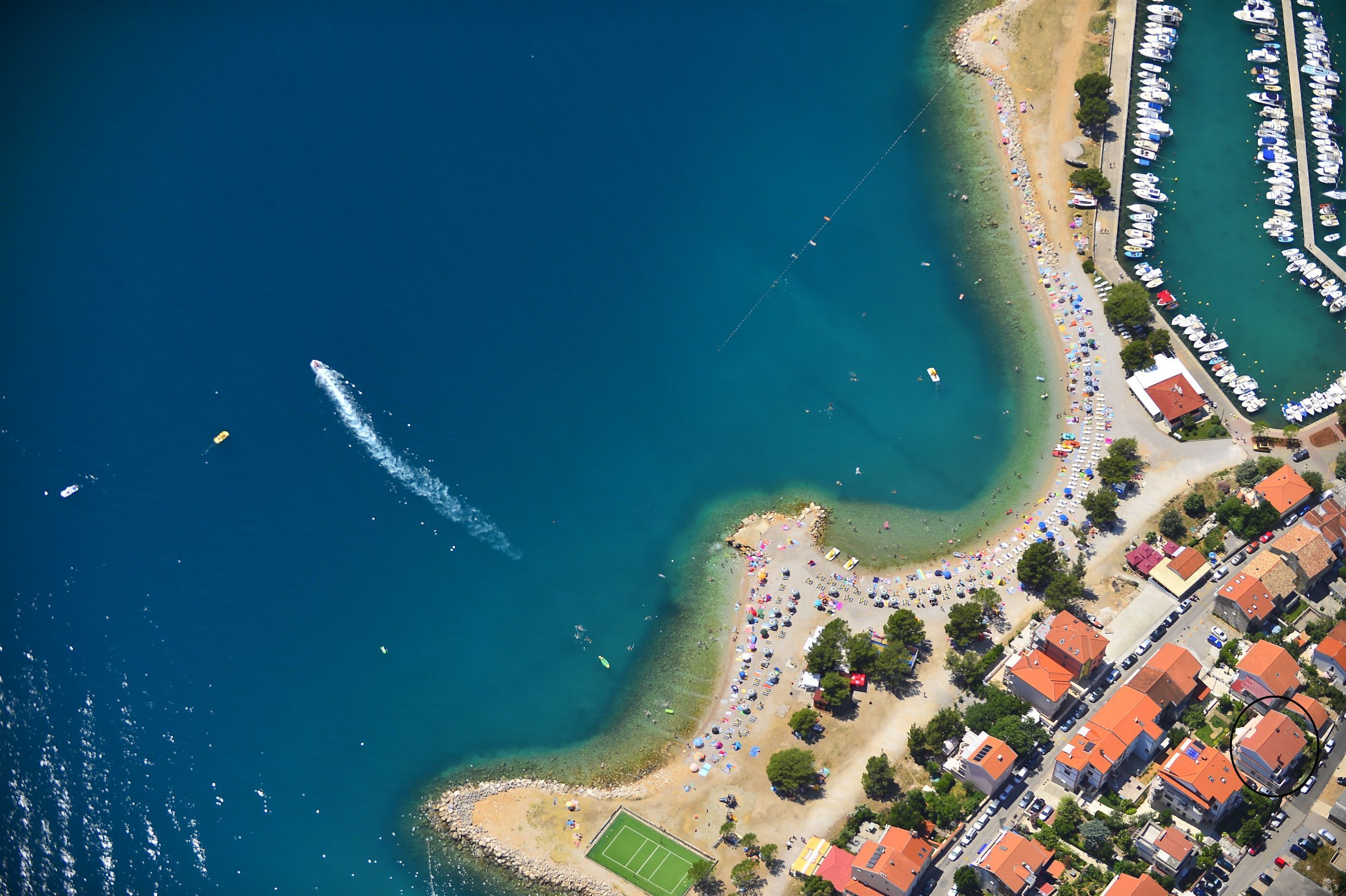 Vista aérea de una zona costera con playa, barcos y edificios residenciales.