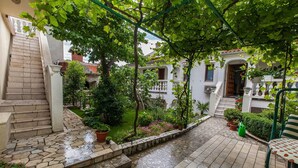 A courtyard with a stone staircase, potted plants, and a bench. - Apartment Marinko (Crikvenica)