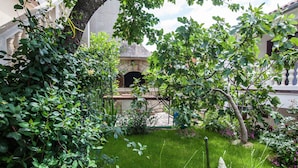 Ein Garten mit einer steingebauten Struktur, möglicherweise ein Kamin, umgeben von üppigem Grün und einem gepflegten Rasen.