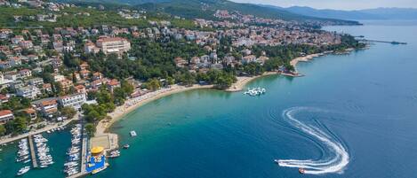An aerial view of a coastal town with a marina, buildings, and a clear sky.
