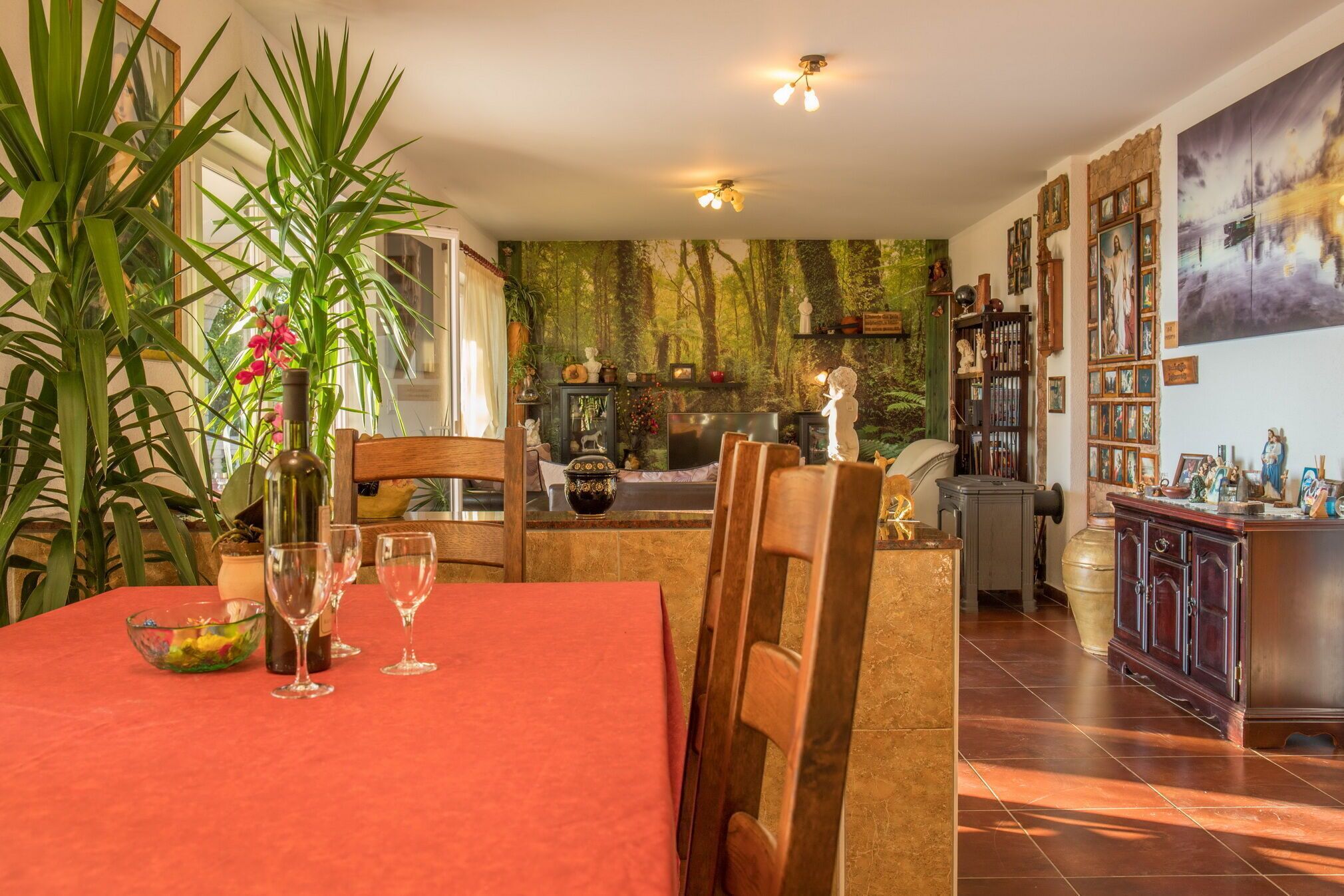 Un comedor con una mesa preparada para cuatro, sillas alrededor, un florero con flores y un cuenco con fruta.