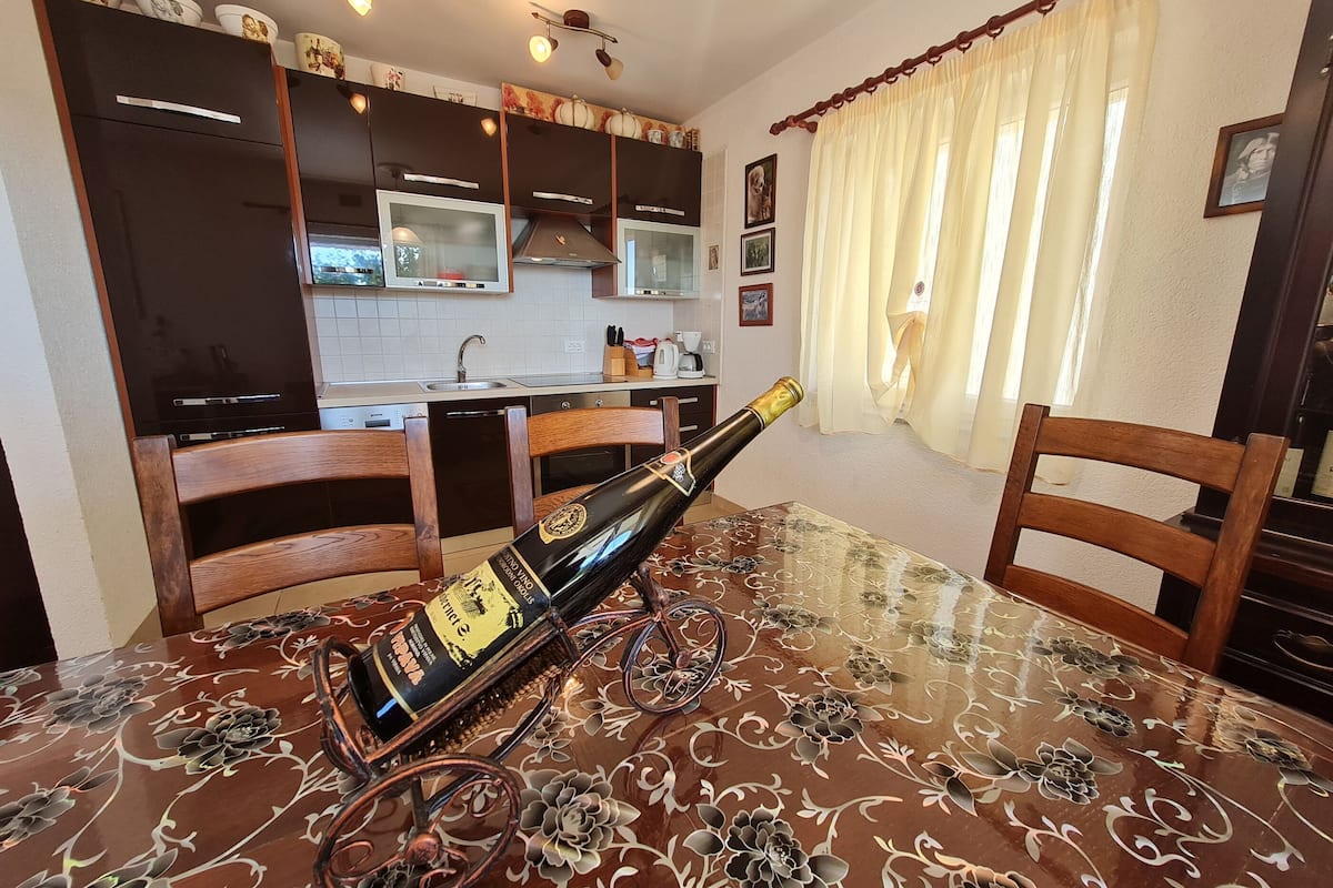 A dining area with a glass table, chairs, and a bottle of wine.