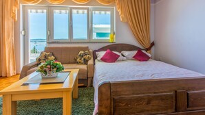 Une chambre à coucher avec un lit, un canapé, une table et une fenêtre avec des rideaux.