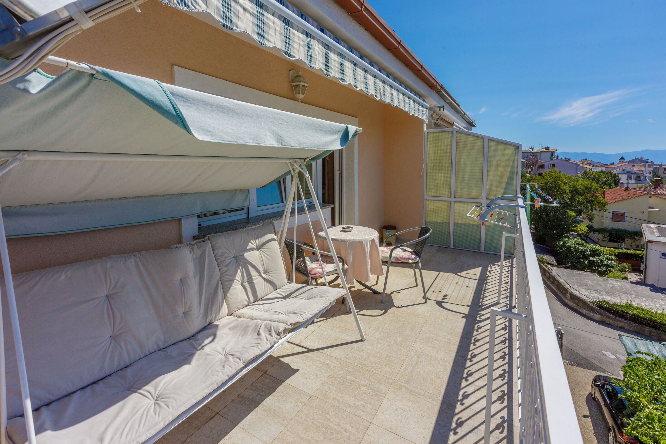 Un balcon avec un canapé confortable, une petite table ronde et une chaise.