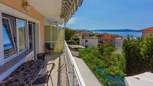 Un balcon avec une table et des chaises, donnant sur un quartier résidentiel et un plan d’eau.