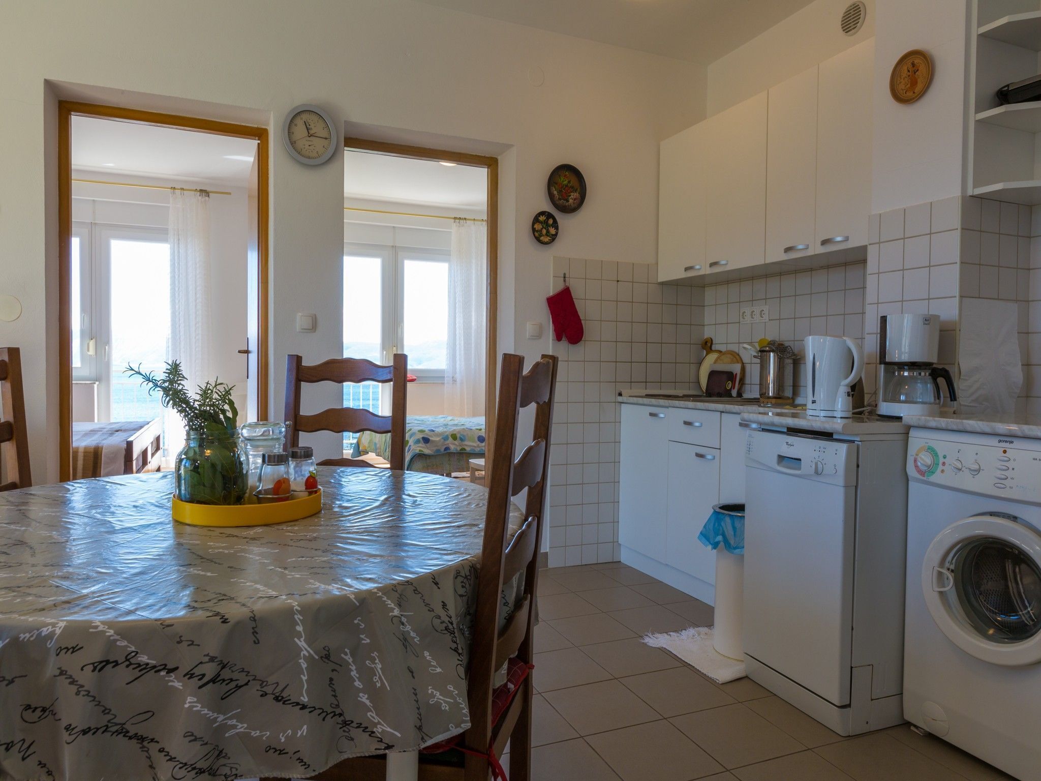 A compact kitchen with white cabinets, a washing machine, and a coffee maker.