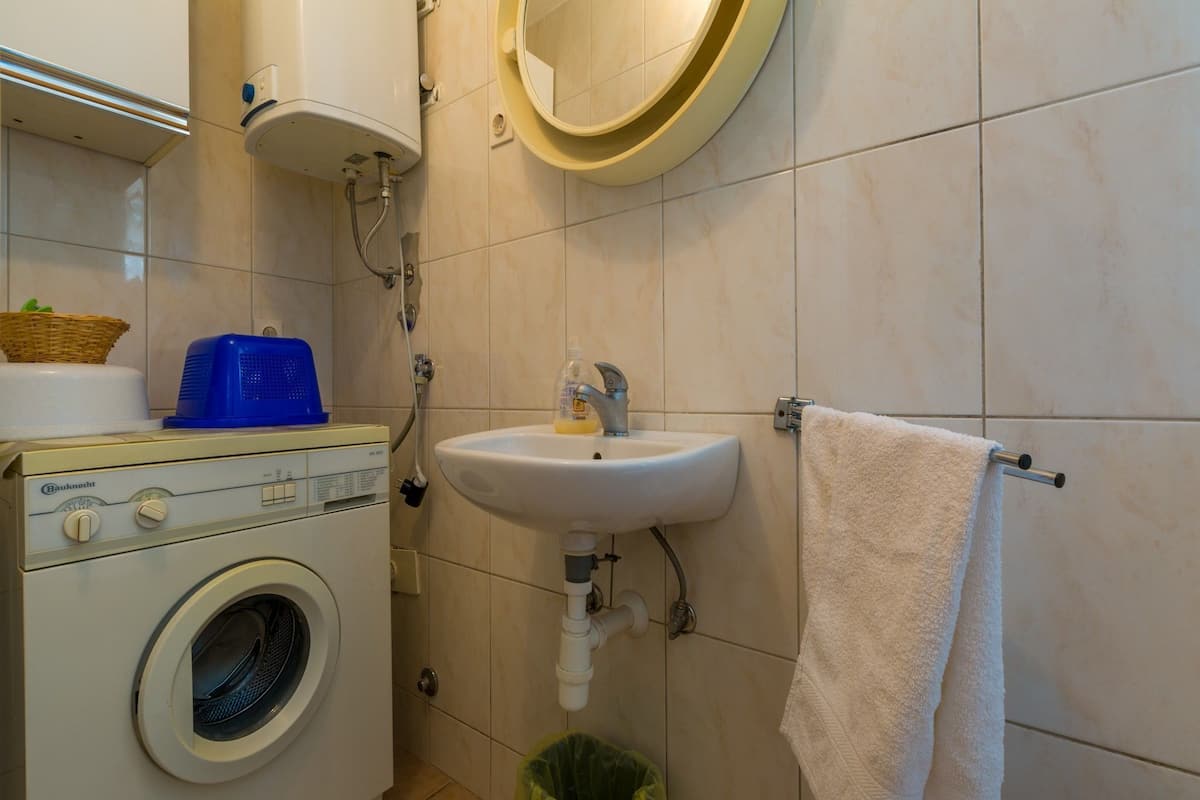 A compact bathroom with a washing machine, a sink, and a towel rack.