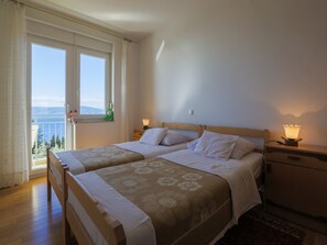 Une chambre double avec deux lits, une table de chevet et une fenêtre donnant sur la mer.