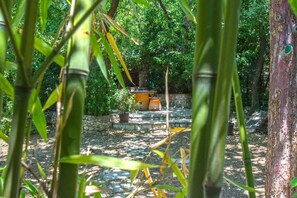 A stone pathway leading to a stone bench surrounded by lush greenery and bamboo plants.
