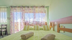 A neatly made bed with green bedding and two rolled towels, a wooden headboard, and a chair to the left. - Apartments Oaza (Dramalj)