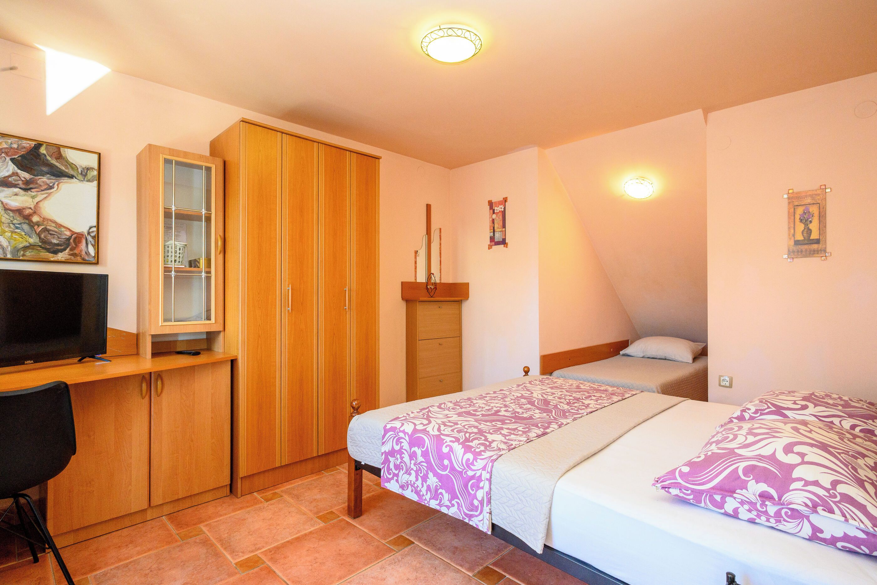 Un dormitorio con cama, escritorio, televisor y armario.