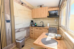 A compact kitchen with wooden cabinets, a microwave, a coffee maker, and a sink.