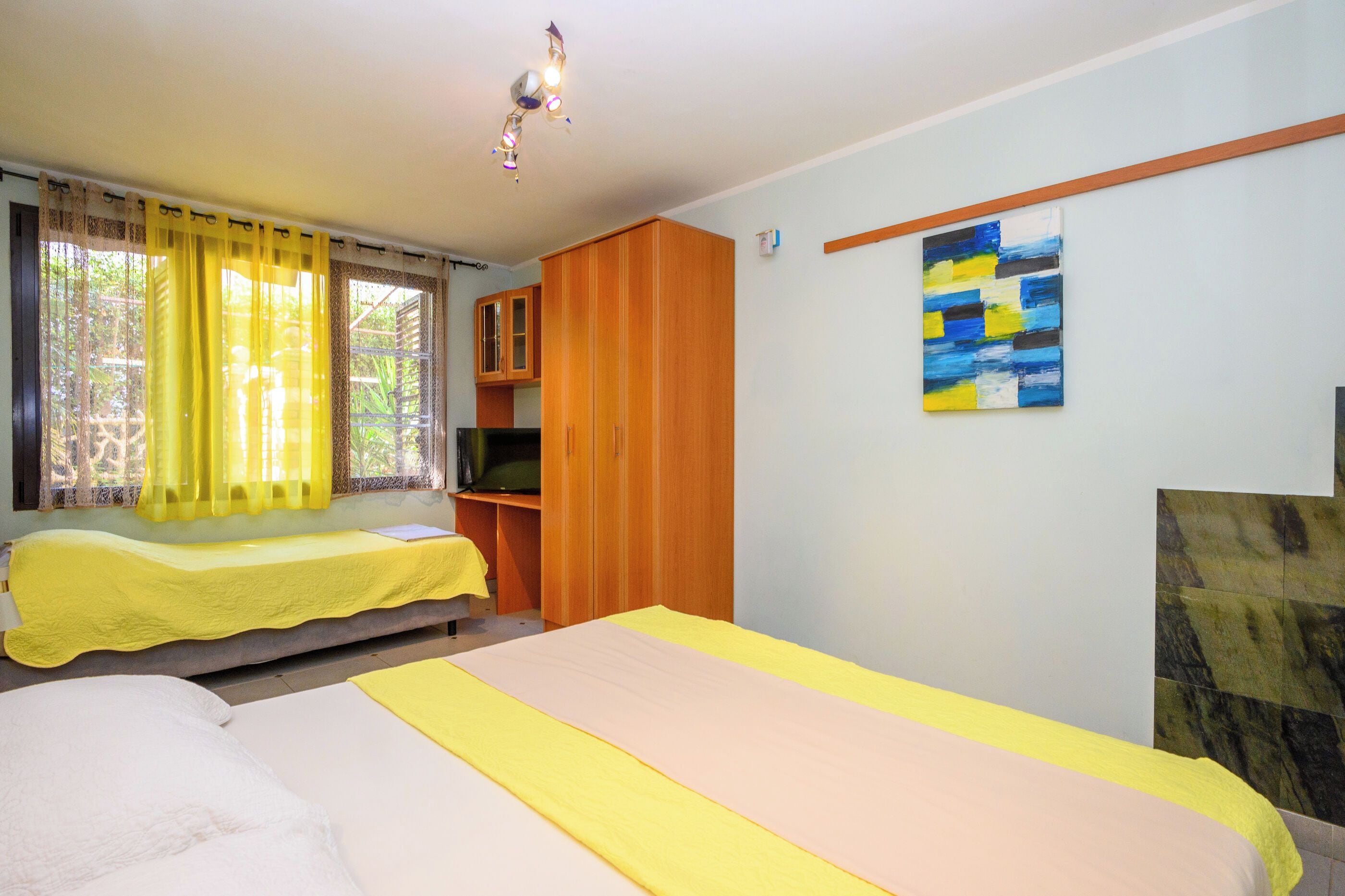 A room with a bed, a desk, a wardrobe, and a painting on the wall.