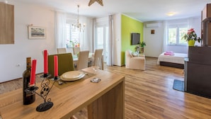 A modern living room with a wooden dining table, a chandelier, and a green accent wall. - Apartments Franny (Novi Vinodolski)