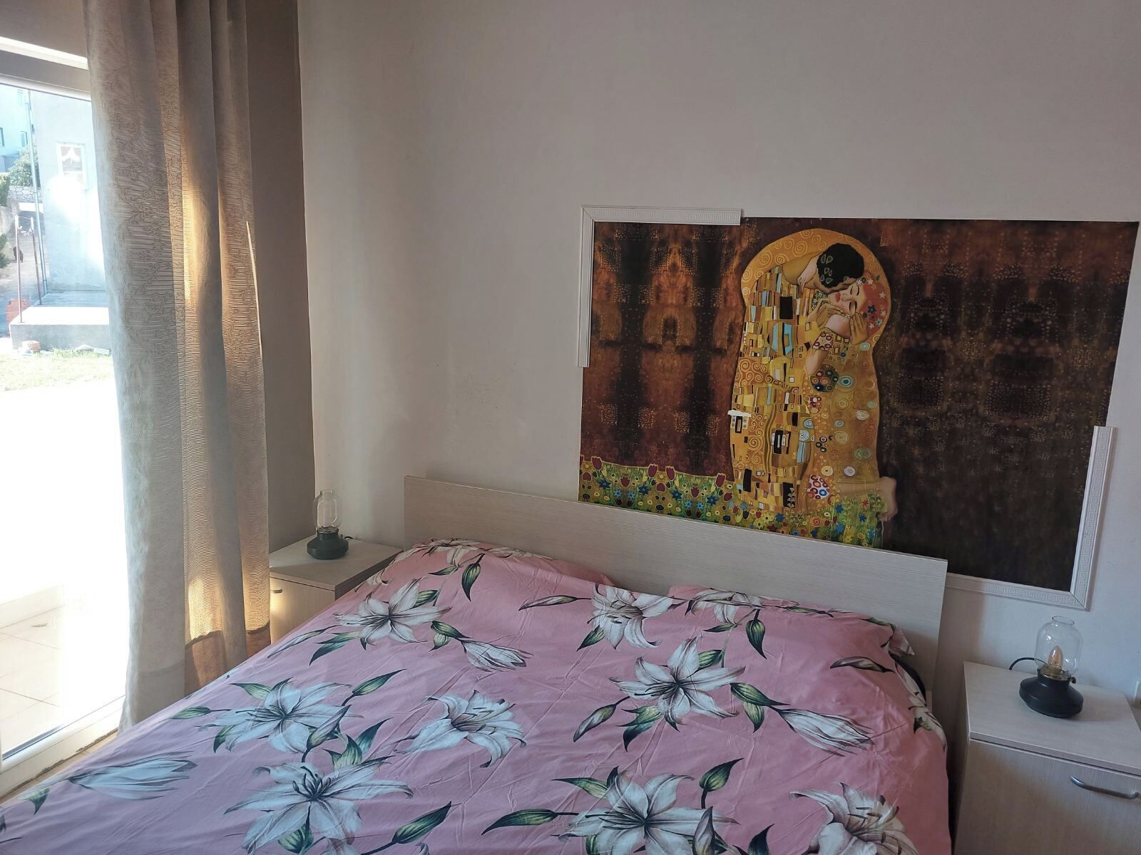 Une chambre à coucher avec un lit, une table de chevet, une lampe et un tableau au mur.