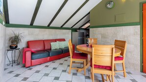 A cozy room with a red sofa, wooden chairs, a small table, and a potted plant. - Apartment Riky (Crikvenica)