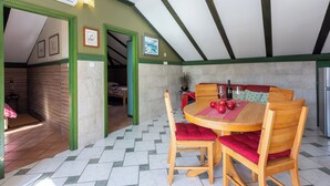A dining area with a wooden table and chairs, a red cushion, and a potted plant. - Apartment Riky (Crikvenica)