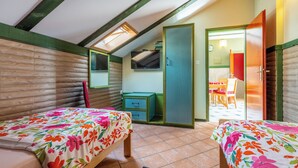 A bedroom with two beds, a TV, and a bathroom visible through an open door. - Apartment Riky (Crikvenica)