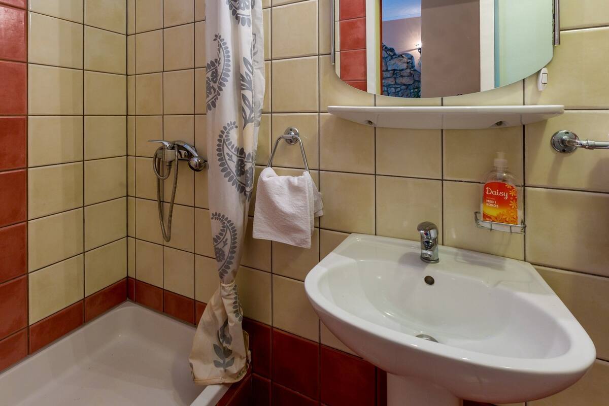 A bathroom with a bathtub, a sink, and a mirror.