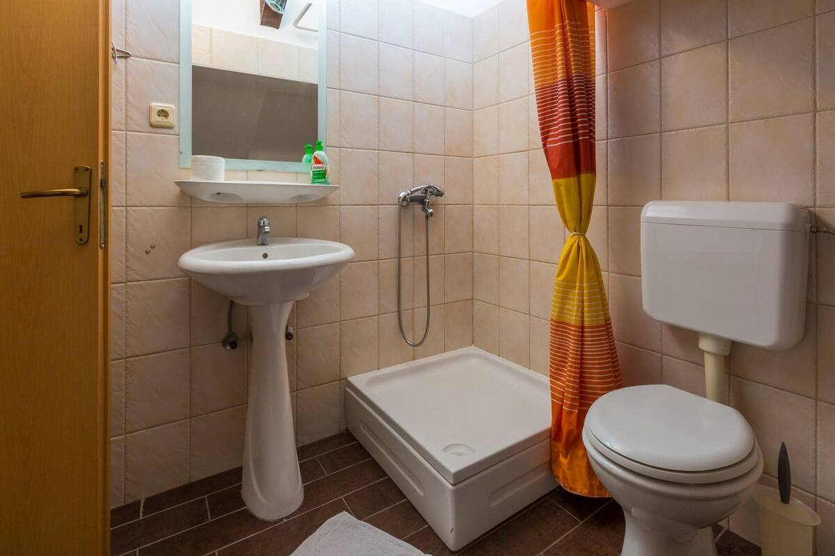 A bathroom with a sink, toilet, shower, and a towel on the floor.