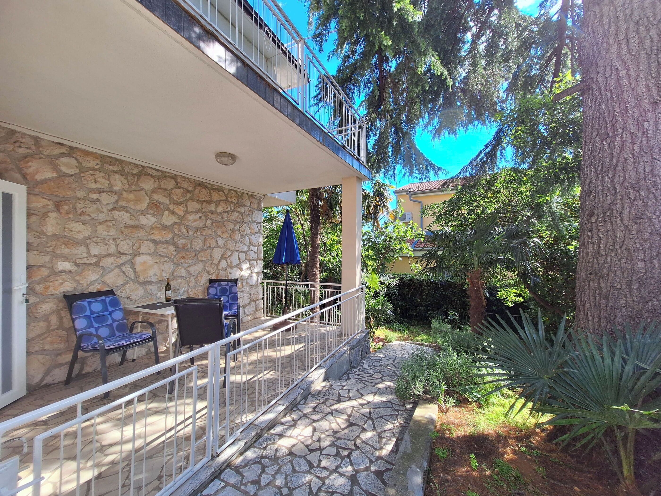 A stone building with a balcony, outdoor seating, and a garden area.