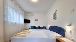 A hotel room with a large bed, a bedside table, a wall-mounted TV, and a window with sheer curtains. - Apartments Danica (Dramalj)