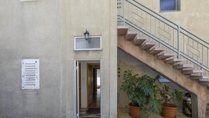 Ein Gebäudeeingang mit Fliesenboden, einer Treppe und zwei Blumentöpfen.