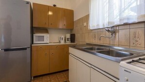Eine kompakte Küche mit Kühlschrank, Mikrowelle, Kaffeemaschine, Spüle und Herd.