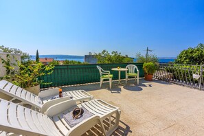 Una terrazza sul tetto con poltrone bianche, un tavolino e una pianta in vaso.