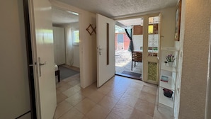 A hallway with a door leading to a room, a small window with curtains, a door with a decorative handle, and a tiled floor. - Apartments Alex (Crikvenica)