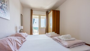 A hotel room with two beds, a view of the outside, and a painting on the wall. - Apartments Alex (Crikvenica)