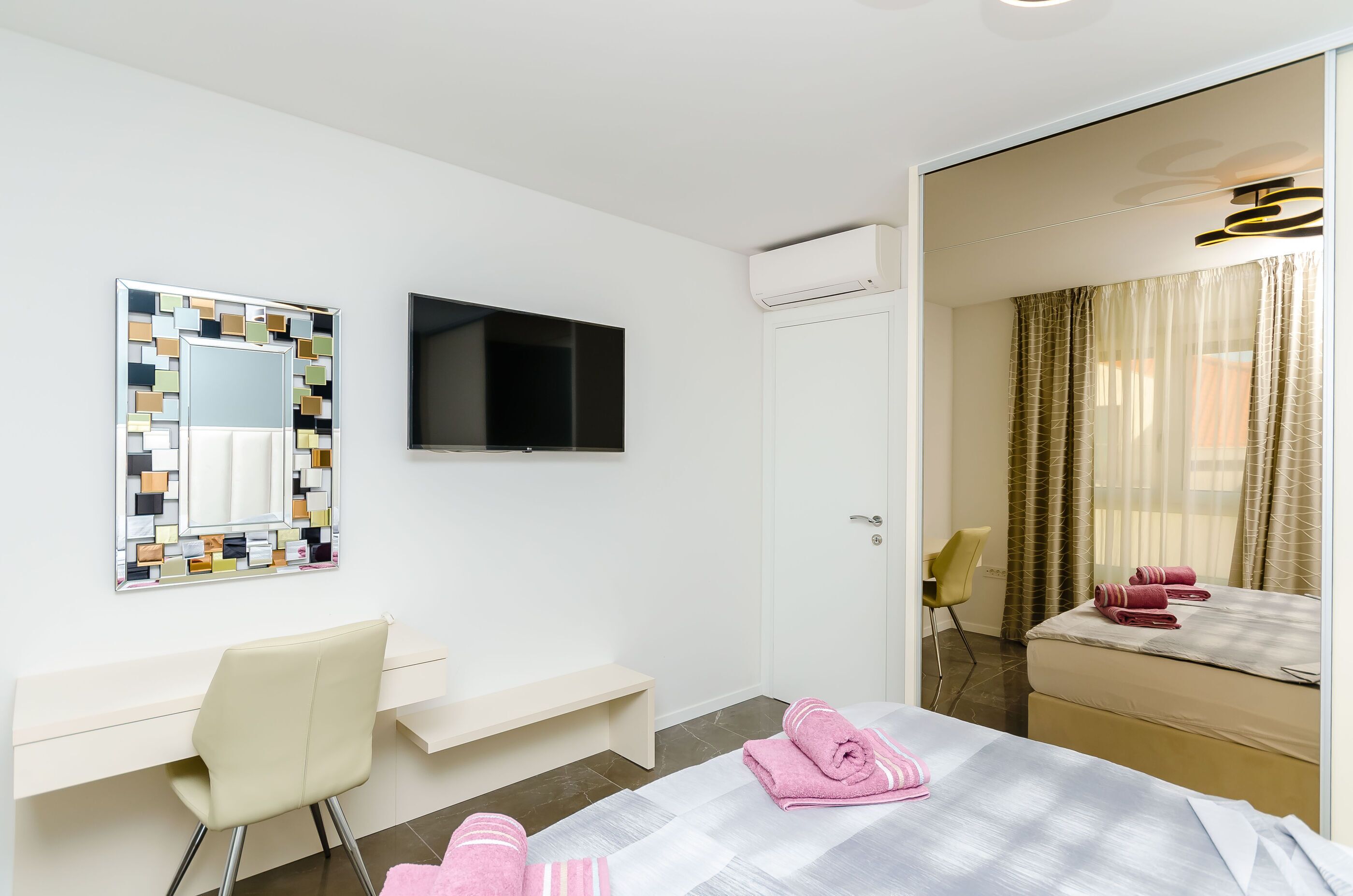 Une chambre d’hôtel avec un lit, un bureau, une chaise, une télévision et un miroir.