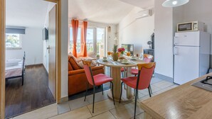 A modern kitchen with a dining area, featuring a round table with chairs, a refrigerator, and a microwave. - Apartments Franka (Crikvenica)