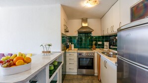 A kitchen with a stainless steel refrigerator, oven, and microwave. There is a fruit bowl on the counter and a green tiled backsplash. - Apartments Franka (Crikvenica)