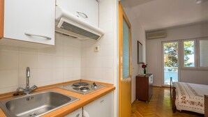 Une cuisine de taille réduite, dotée d’un évier à deux bacs, d’une cuisinière et d’un plan de travail en bois.