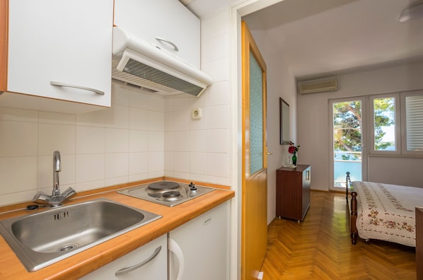 A compact kitchen with a double sink, a stove, and a wooden countertop. - Apartment and Rooms Franka (Sibenik)