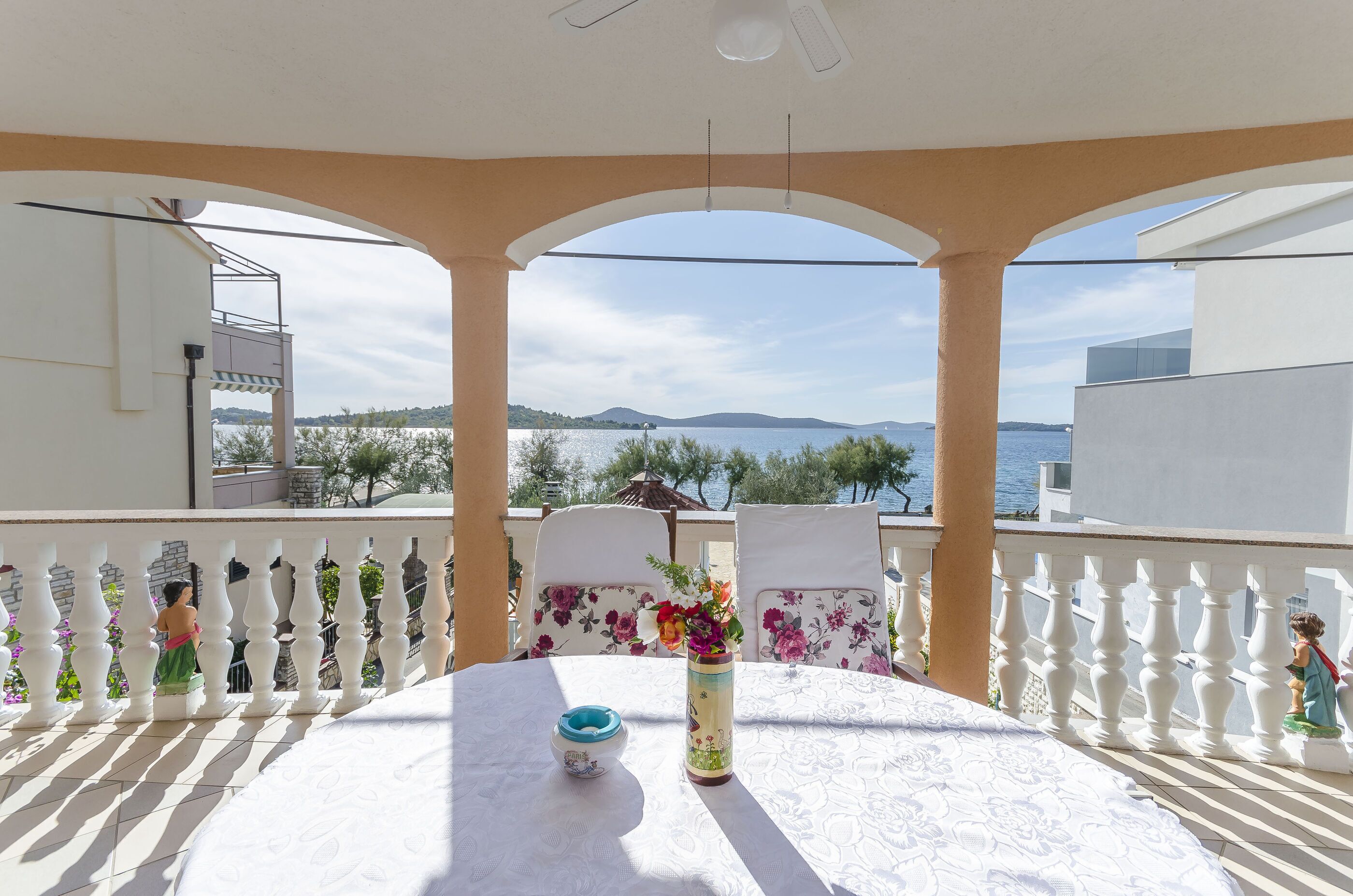 Un balcón con mesa, sillas y vista al mar.