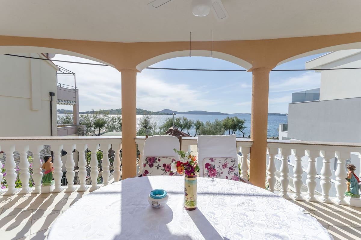 Ein Balkon mit Tisch, Stühlen und Meerblick.