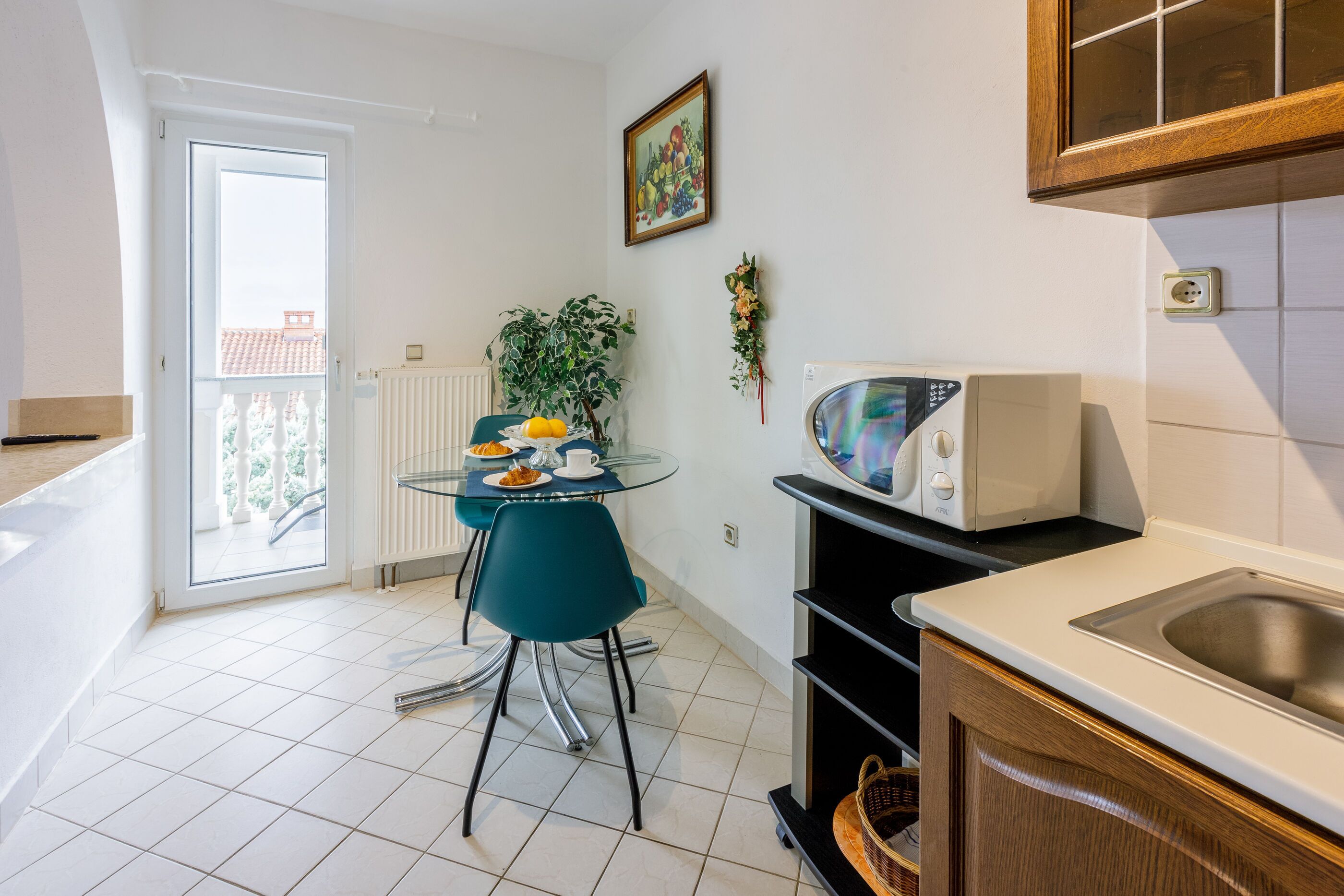 Cocina compacta con una mesa de vidrio, microondas y lavamanos.
