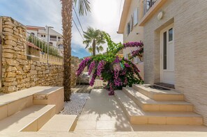 A narrow street with a stone wall on one side and a building with a balcony on the other. - Villa Urban (Okrug Gornji)