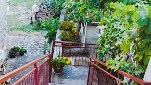 A staircase with red railings leading to a garden area with potted plants and a yellow car parked nearby. - Apartment Anica (Starigrad - Paklenica)