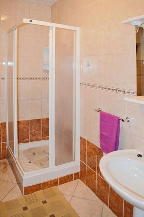 A bathroom with a shower, sink, and a towel rack. - Apartment Anica (Starigrad - Paklenica)