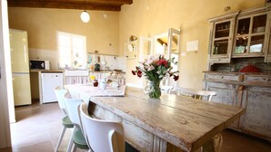 Une cuisine avec une table en bois, des chaises et un vase de fleurs.