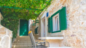A narrow stone pathway leading to a building with green shutters and a bench. - House Dinko (Bol)