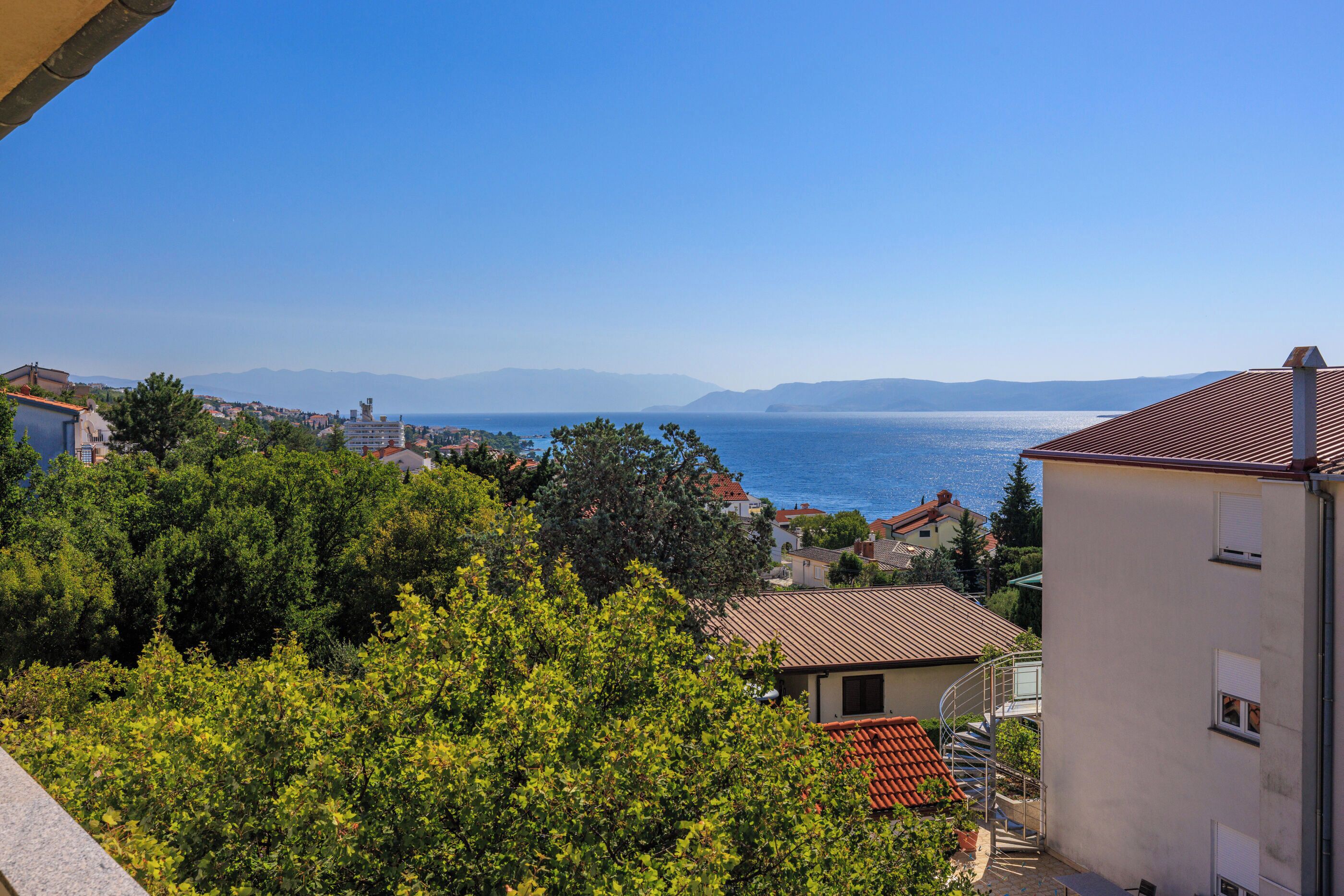A coastal town with buildings, trees, and a clear view of the sea.